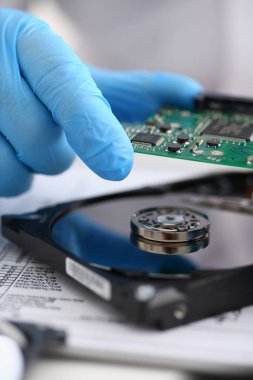 Erkek tamirci mavi eldiven giymiş bir sabit disk tutuyor