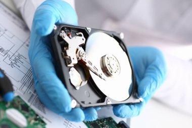 Erkek tamirci mavi eldiven giymiş bir sabit disk tutuyor