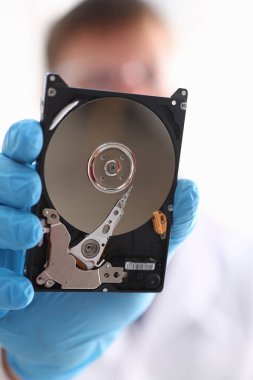 Erkek tamirci mavi eldiven giymiş bir sabit disk tutuyor