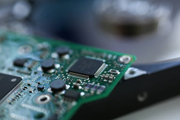 Tablero electrónico con microchips sobre un fondo de disco duro — Foto de Stock