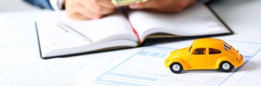 Masanın üzerinde yatan sarı oyuncak araba ile sigorta formu