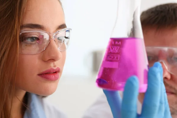 Női kémikus tart kémcsőbe üveg a kezében túlfolyik a folyadék — Stock Fotó