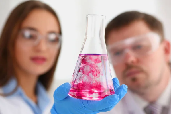 女性化学者を保持する彼の手でガラスの試験管液体のオーバーフロー — ストック写真