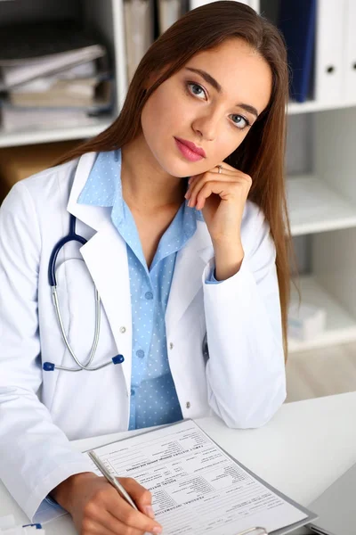 Ärztin hält silbernen Stift und Block im Arm — Stockfoto