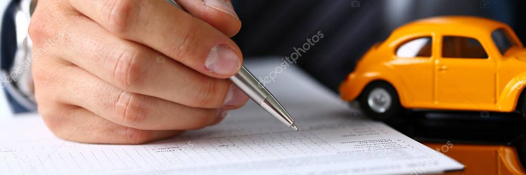 Male arm in suit sign insurance form lying on table