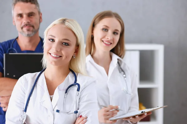 Grupo de médicos posando orgullosamente en fila y mirando a la cámara —  Fotos de Stock