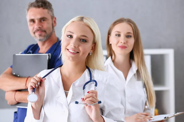 Grupo de médicos posando orgullosamente en fila y mirando a la cámara —  Fotos de Stock