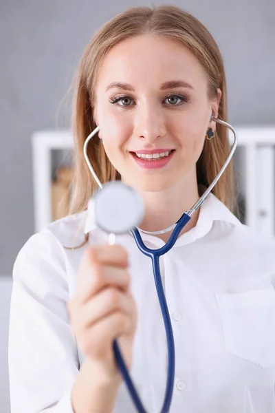 Hermosa mujer sonriente médico en la mano estetoscopio cabeza —  Fotos de Stock