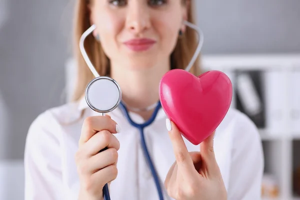 Schöne lächelnde Ärztin hält rotes Herz im Arm — Stockfoto