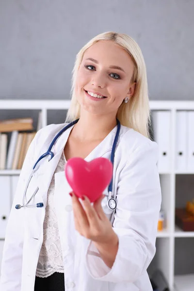 Hermoso médico sonriente en brazos corazón rojo —  Fotos de Stock