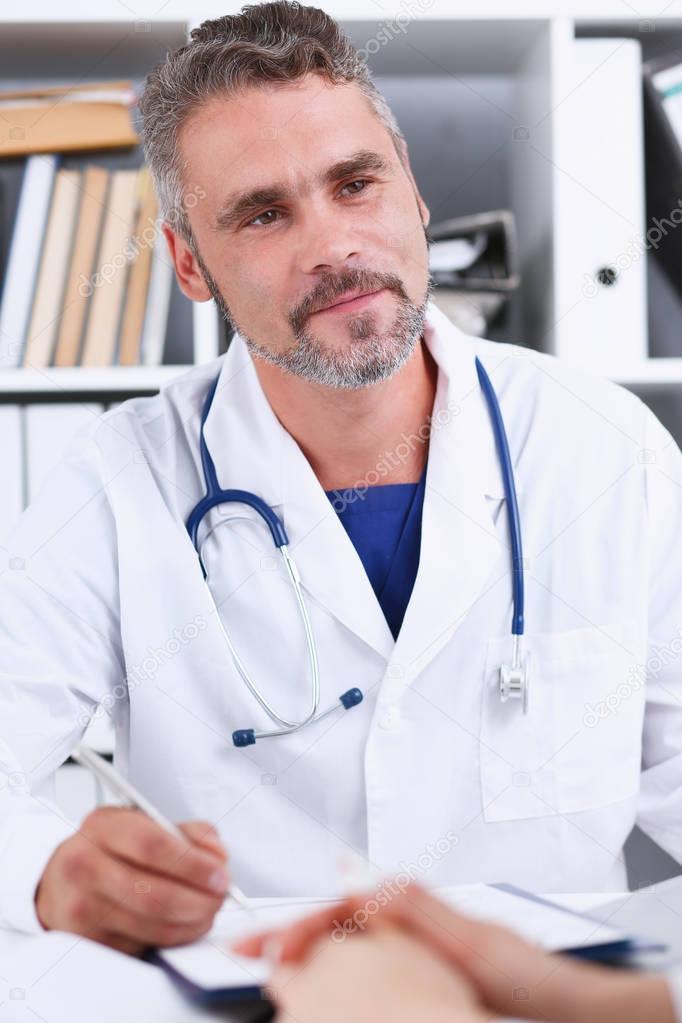 Smiling handsome mature doctor communicate with patient