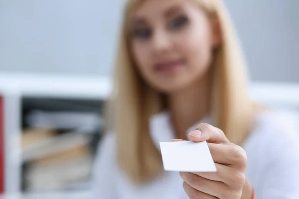 Smiling businesswoman holding hand in white shirt give blank calling card