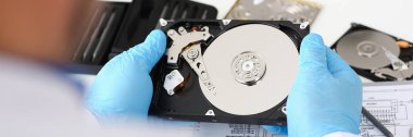 Erkek tamirci mavi eldiven giymiş bir sabit disk tutuyor