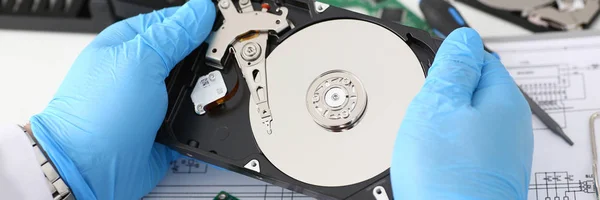 male repairman wearing blue gloves is holding a hard drive