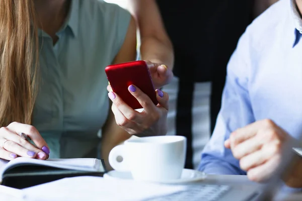 Smartphone em uma mão de mulheres em uma janela vermelha — Fotografia de Stock