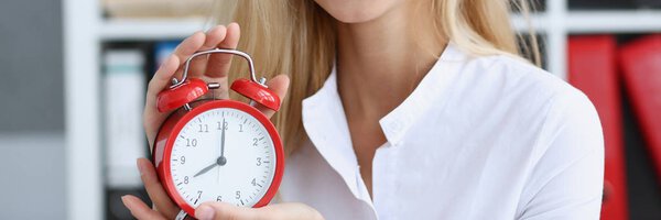 Smiling business woman holding in hand clock