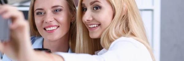 Due donne d'affari in ufficio sorridono e fanno selfie — Foto Stock