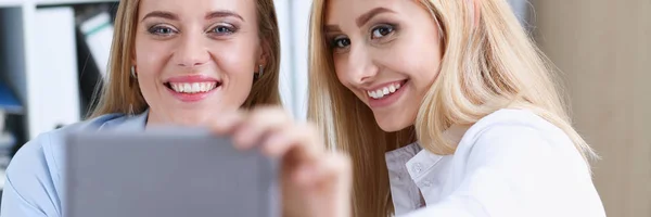 Duas mulheres de negócios no escritório sorriem e fazem selfie — Fotografia de Stock