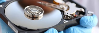 Erkek tamirci mavi eldiven giymiş bir sabit disk tutuyor