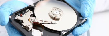 Erkek tamirci mavi eldiven giymiş bir sabit disk tutuyor