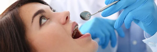 Жінка на прийомі чоловіка-стоматолога, який вивчає зуби — стокове фото