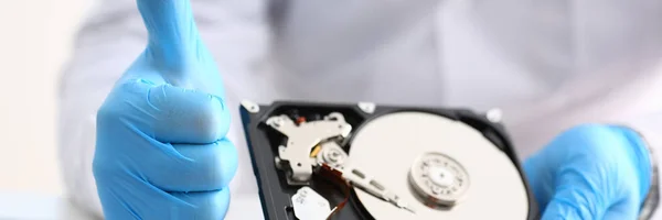 Male repairman wearing blue gloves is holding hard drive