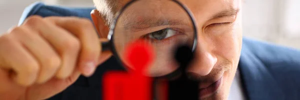 Homem de terno olhar thru loupe em estatuetas closeup — Fotografia de Stock