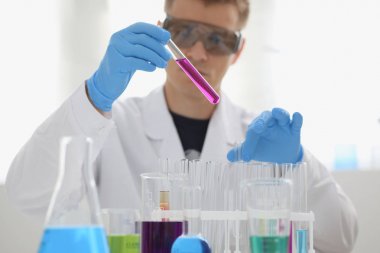 Bir erkek kimyager tüp cam tutar