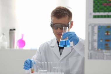 Bir erkek kimyager tüp cam tutar