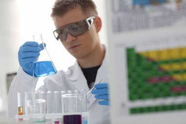 Bir erkek kimyager tüp cam tutar