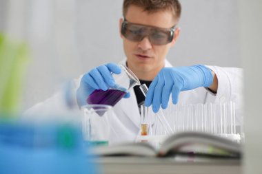 Bir erkek kimyager tüp cam tutar