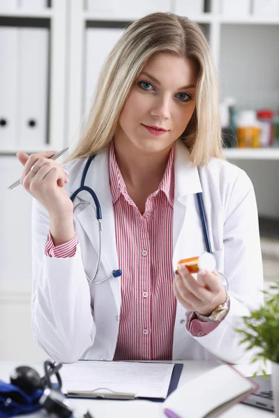 Schön lächelnde Ärztin sitzt am Arbeitsplatz — Stockfoto