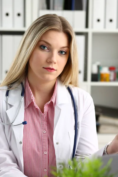 Красива усміхнена жінка-лікар сидить на робочому місці — стокове фото