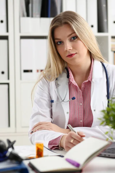 Hermosa mujer sonriente médico sentarse en el lugar de trabajo — Foto de Stock