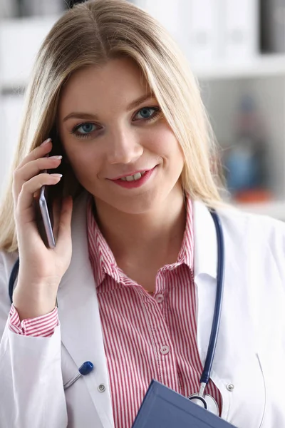 Beautiful female blond doctor talking on phone