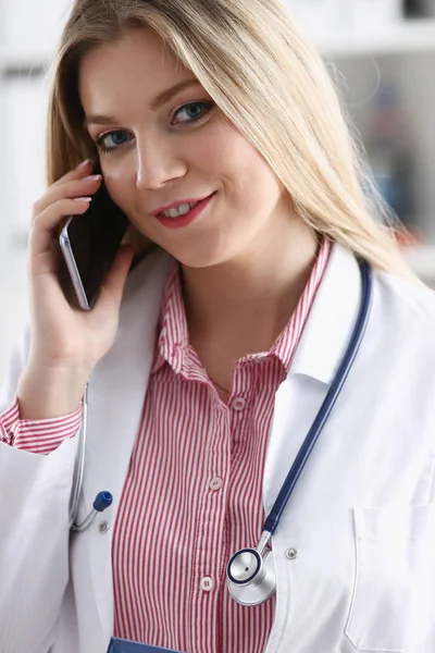 Beautiful female blond doctor talking on phone