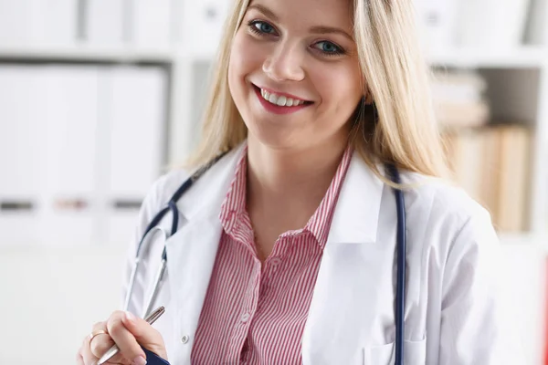 Hermosa mujer sonriente médico sentarse en el lugar de trabajo —  Fotos de Stock