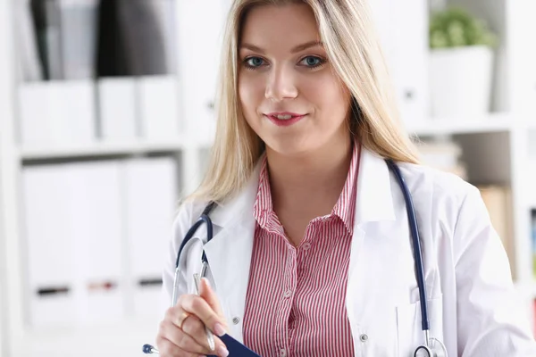 Vackra leende kvinnliga läkare, sitta på arbetsplatsen — Stockfoto