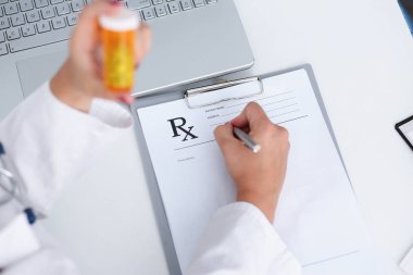 Kadın doktor el kavanoz hapları tutun ve yazmak