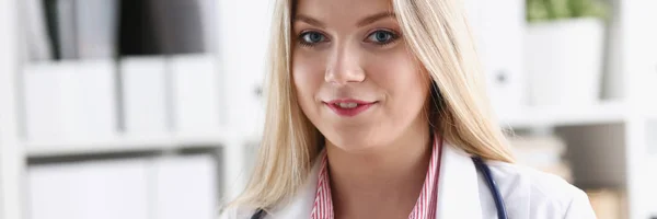 Bonita sorridente médico feminino sentar no local de trabalho — Fotografia de Stock