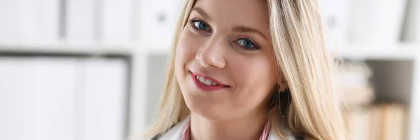 Красивая улыбающаяся женщина врач сидит на рабочем месте — стоковое фото