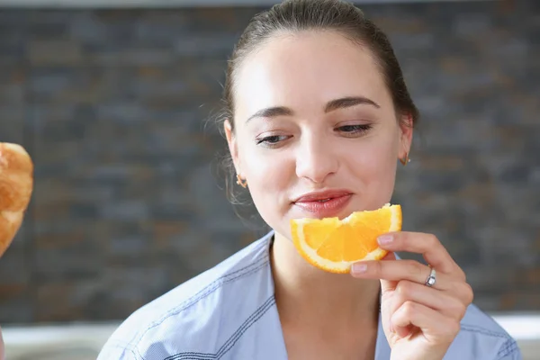 Hermosa morena sonriente mujer comer en rodajas naranja —  Fotos de Stock