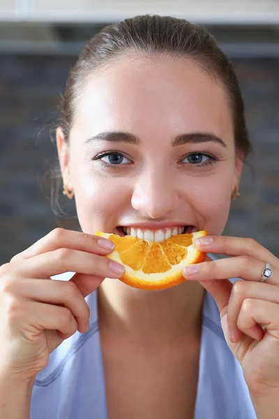 Linda morena sorrindo mulher comer laranja fatiada — Fotografia de Stock