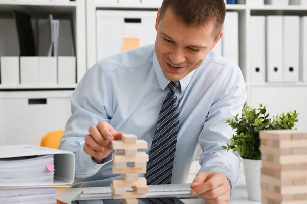 Businessman plays in a strategy of jenga hand
