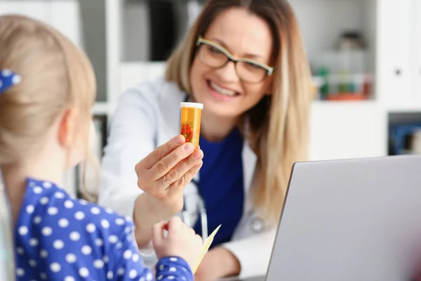 Красивая улыбающаяся женщина-врач держит в руках таблетку — стоковое фото