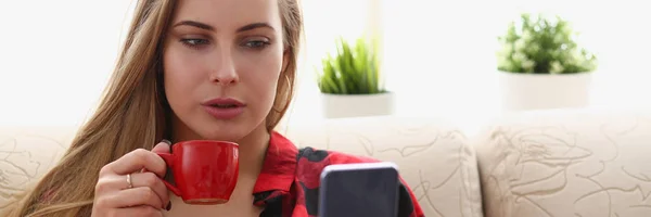 Женщина пьет кофе и смотрит на ноутбук — стоковое фото