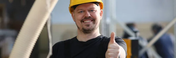 Pekerja tersenyum dengan helm kuning menunjukkan tanda konfirmasi — Stok Foto
