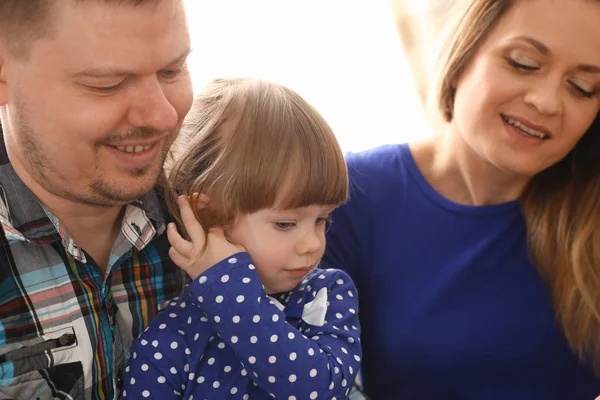 Lyckliga föräldrar med dotter på soffan hemma — Stockfoto