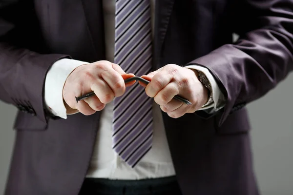 Mann in Anzug und Krawatte biegen Nagel mit Armen Nahaufnahme — Stockfoto