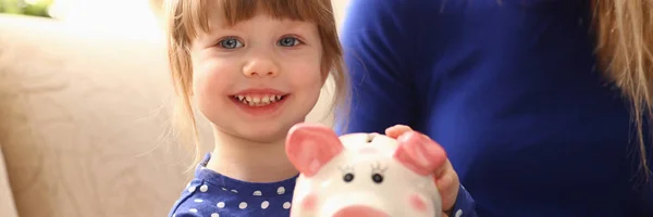 Niño niña brazo poner monedas en piggybank — Foto de Stock